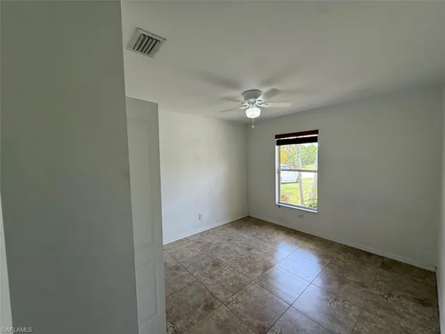 Spare room with a ceiling fan and tile patterned floors