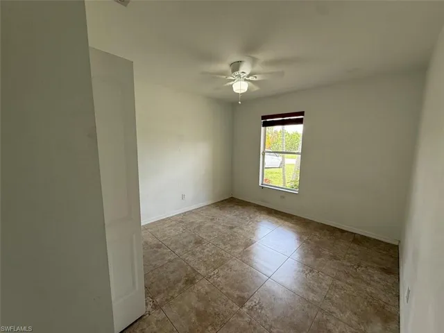 Tiled spare room with ceiling fan and baseboards