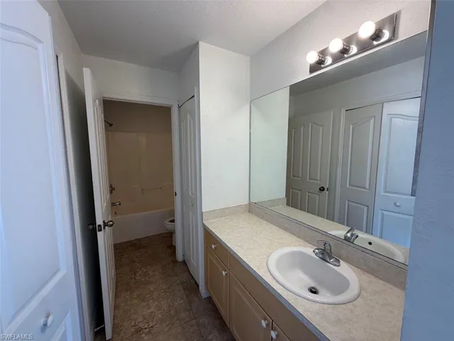 Bathroom with vanity, a textured wall, and a textured ceiling