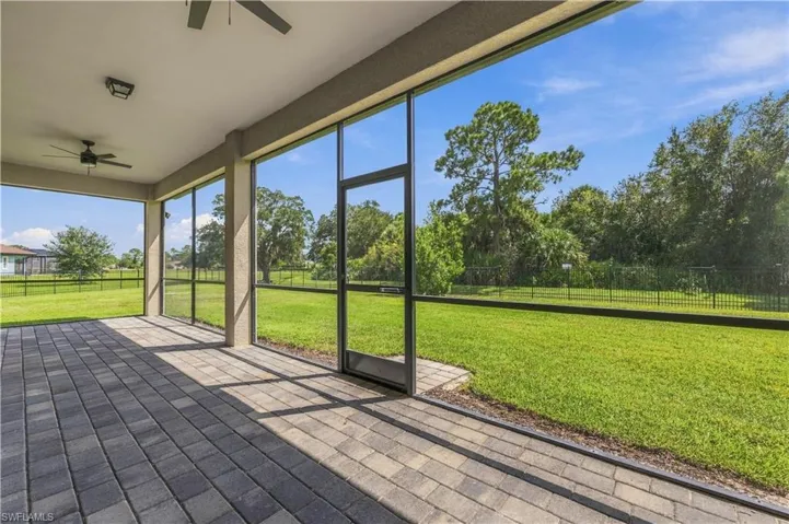 Expansive screened patio featuring pavers, dual ceiling fans, and a large grassy area
