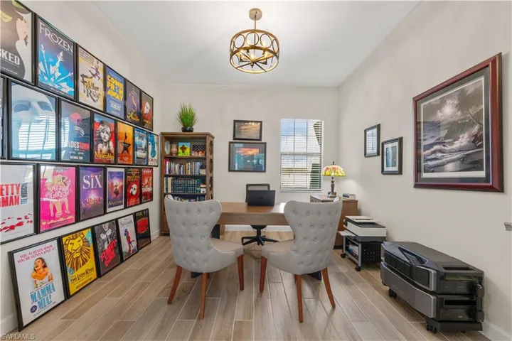 Recessed lighting, wood-finish flooring, and a circular drum chandelier illuminate this versatile room
