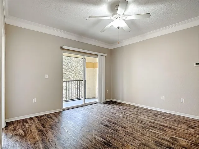 Spare room with a ceiling fan, a textured ceiling, dark wood-style floors, and ornamental molding