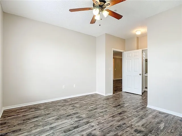 Spare room featuring dark wood-type flooring, ceiling fan, and a textured ceiling