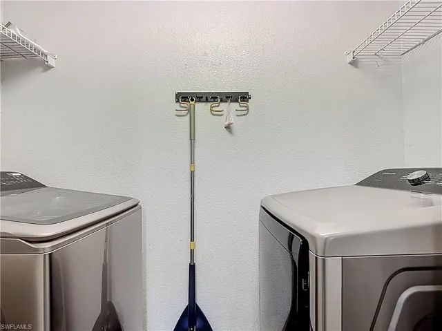 Laundry area featuring washer and clothes dryer and a textured wall