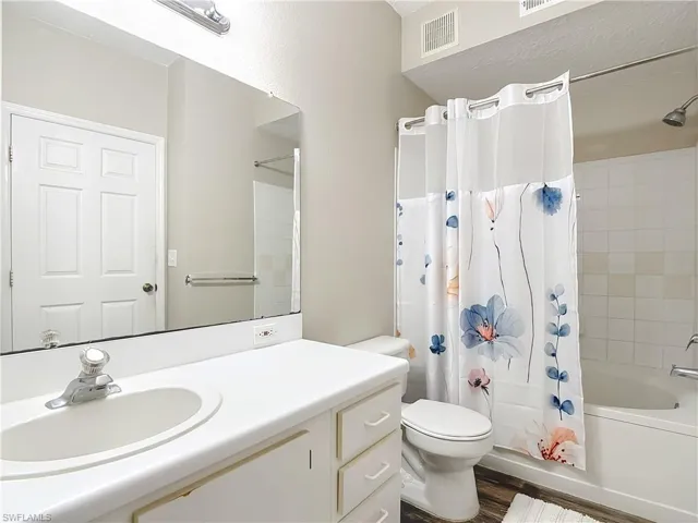Bathroom with shower / tub combo, vanity, and dark wood finished floors