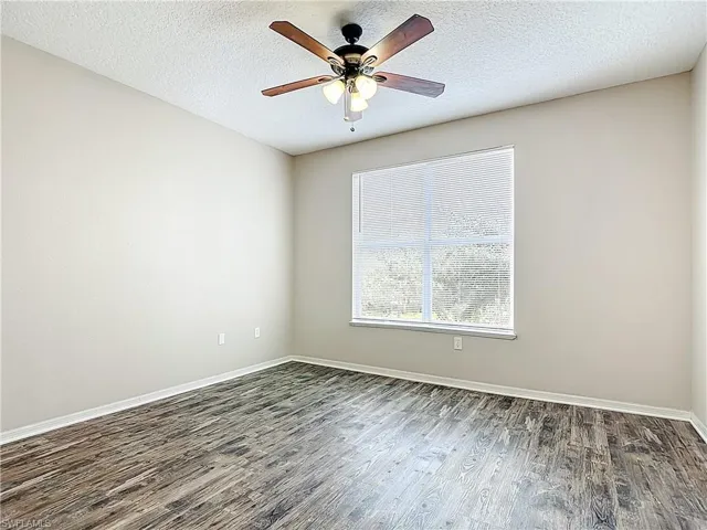 Spare room with wood finished floors, a textured ceiling, and a ceiling fan