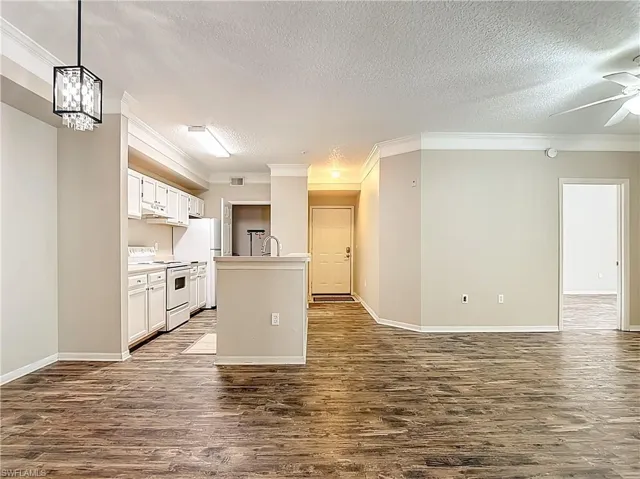 Kitchen with white cabinets, light countertops, white electric range, crown molding, and a textured ceiling