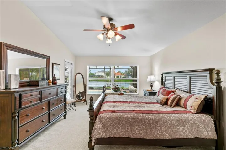 Carpeted bedroom featuring ceiling fan and vaulted ceiling