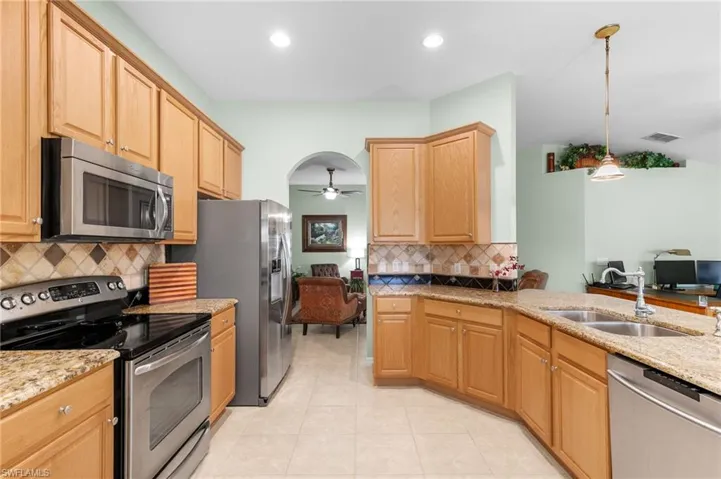 Kitchen with light tile flooring, stainless steel appliances, backsplash, ceiling fan, and sink