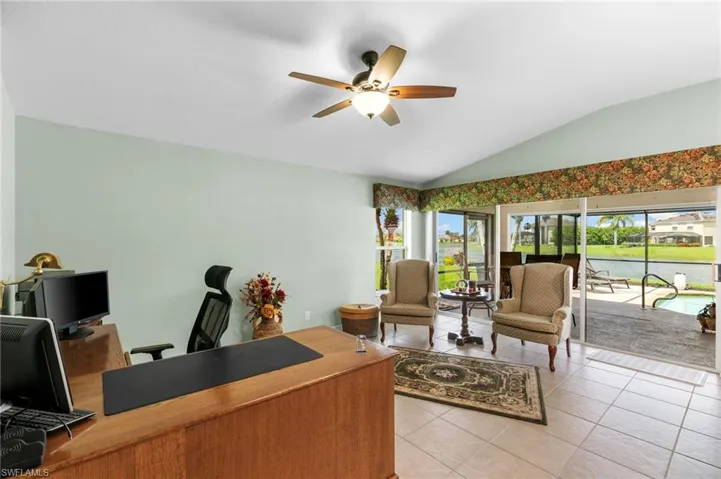 Home office with tile floors, ceiling fan, and vaulted ceiling
