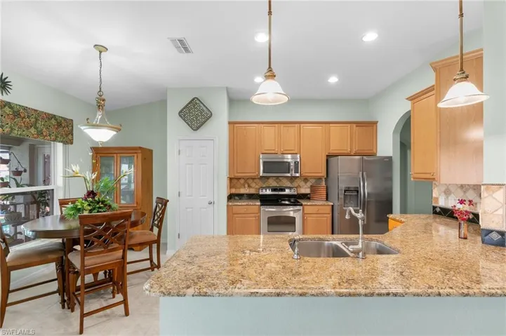 Kitchen featuring hanging light fixtures, light tile floors, backsplash, and appliances with stainless steel finishes