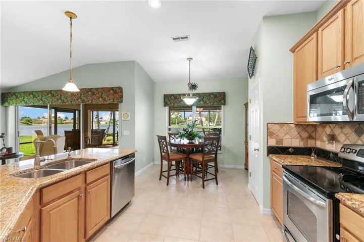 Kitchen with appliances with stainless steel finishes, sink, light tile flooring, and hanging light fixtures