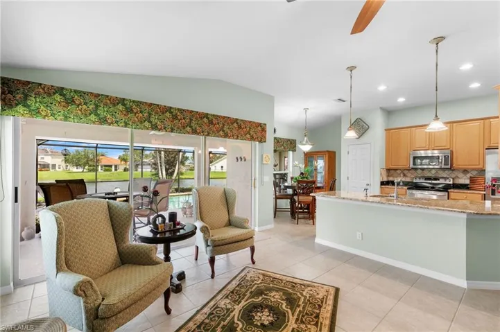 Living room featuring vaulted ceiling, sink, and light tile floors