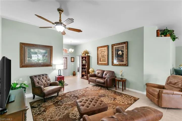 Tiled living room featuring ceiling fan with notable chandelier