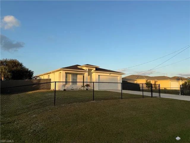 Rear view of house featuring stucco siding, an attached garage, and driveway