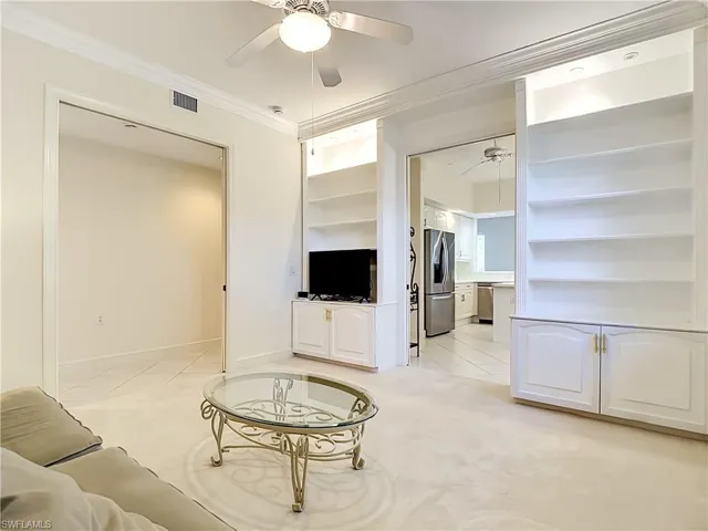 Living area featuring built-in shelving with integrated lighting and lower cabinetry