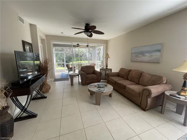 Living area with a ceiling fan, light tile patterned floors, and a sunroom