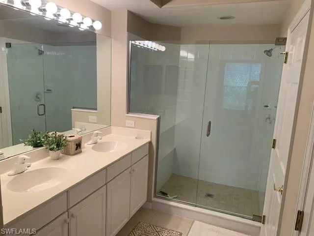 Full bath featuring tile patterned floors, a shower stall, and double vanity