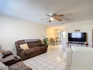 Living area with ceiling fan, a textured ceiling, and tile patterned flooring
