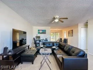 Living room featuring a textured ceiling, a ceiling fan, and light tile patterned floors