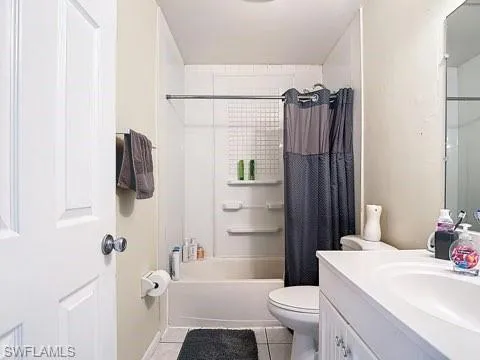 Full bathroom with vanity, shower / bath combo with shower curtain, and light tile patterned floors