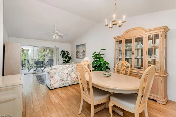 Dining room featuring light wood-type flooring, lofted ceiling, a chandelier, and a ceiling fan