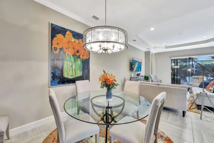 Dining room featuring a raised ceiling, ornamental molding, and an inviting chandelier