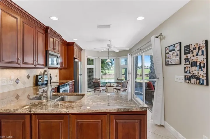 This stunning space showcases beautiful granite countertops, a tumbled marble backsplash with under-cabinet lighting, stainless steel appliances, custom cabinetry, and awe-inspiring views