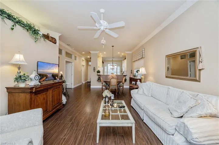 Living room with dark wood-type flooring, ornamental molding, ceiling fan, and recessed lighting