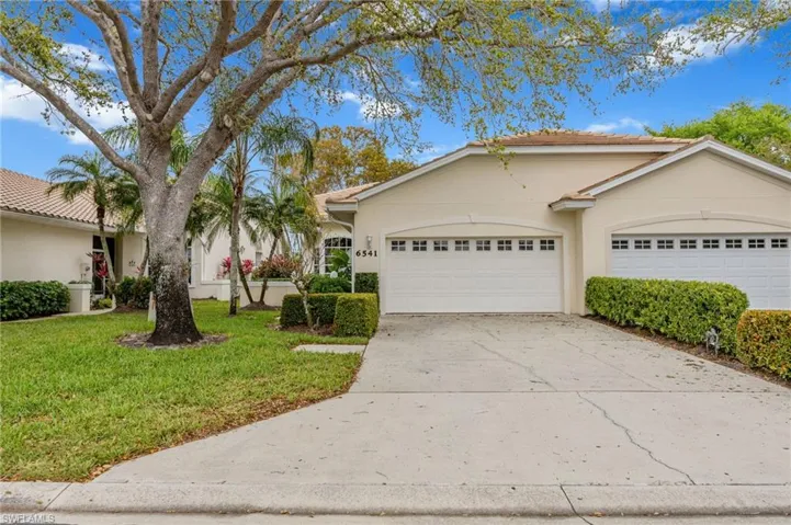 View of front of home featuring stucco siding, driveway, a front yard, and an attached garage