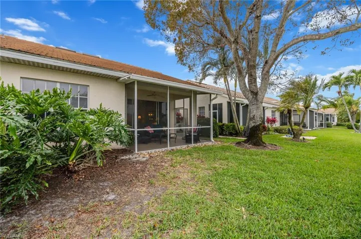 Back of property featuring stucco siding, a sunroom, a yard, and a ceiling fan