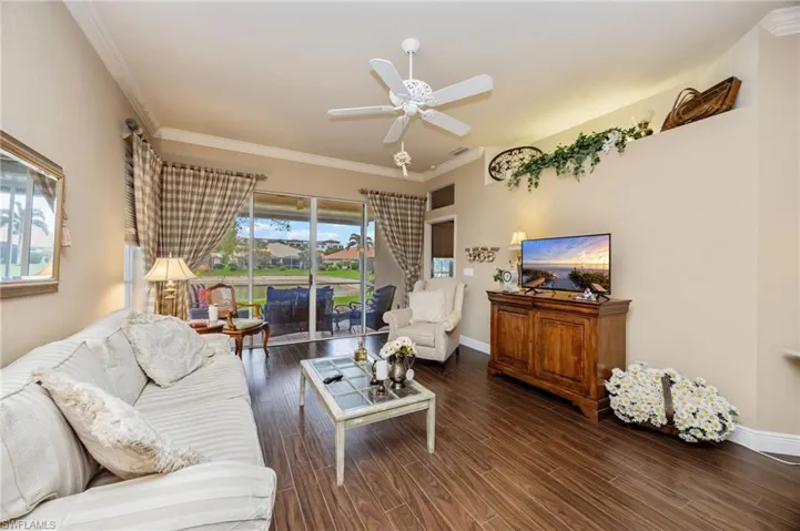 Living area with dark wood-style flooring, crown molding, and a ceiling fan