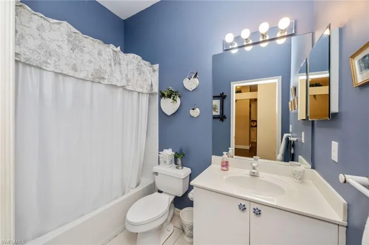 Full bath featuring vanity, shower / bath combo with shower curtain, and light tile patterned floors
