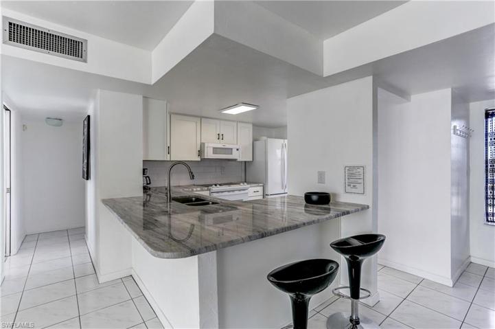 New Kitchen with quartz counters, white wood cabinetry, white appliances.