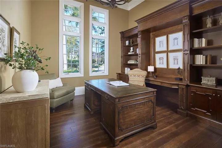 Home office featuring dark wood-style flooring, built in study area, and ornamental molding