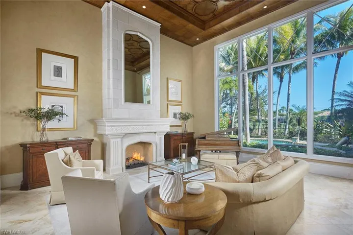 Sitting room with a lit fireplace, wooden ceiling, a high ceiling, and recessed lighting