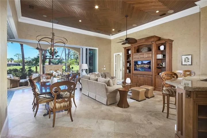 Living room featuring ornamental molding, a ceiling fan, a textured wall, a chandelier, and a high ceiling