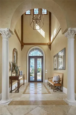 Entrance foyer with inlaid floor details, ornate columns, plenty of natural light, and a high ceiling