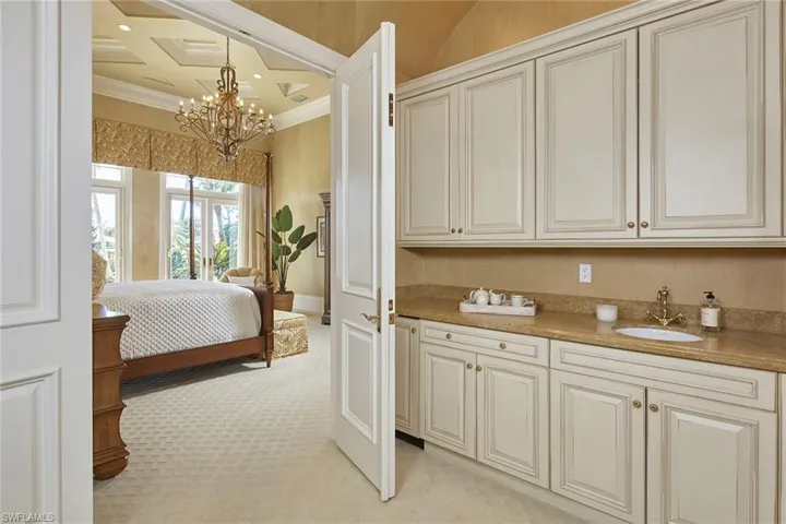 Bedroom with crown molding, light colored carpet, and a chandelier