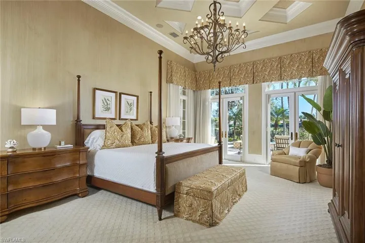 Carpeted bedroom with a high ceiling, access to outside, ornamental molding, a chandelier, and french doors