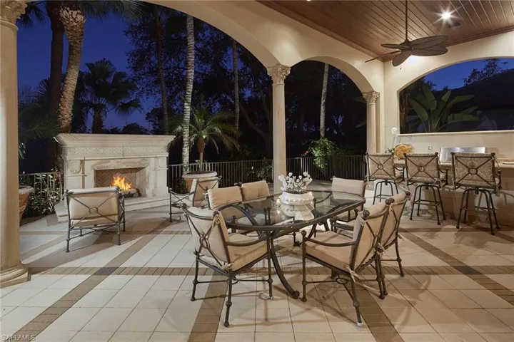 Patio at twilight with ceiling fan, a high end fireplace, outdoor dining area, and a patio