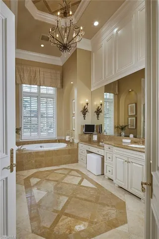 Bathroom featuring inlaid floor details, vanity, a garden tub, recessed lighting, and ornamental molding