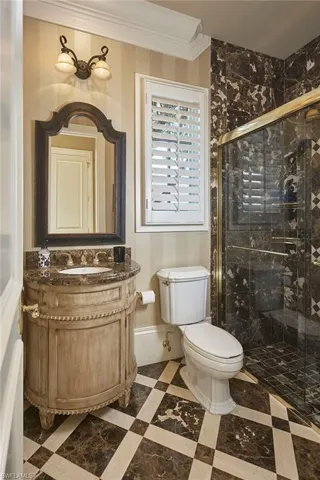 Bathroom featuring a stall shower, vanity, ornamental molding, and wallpapered walls