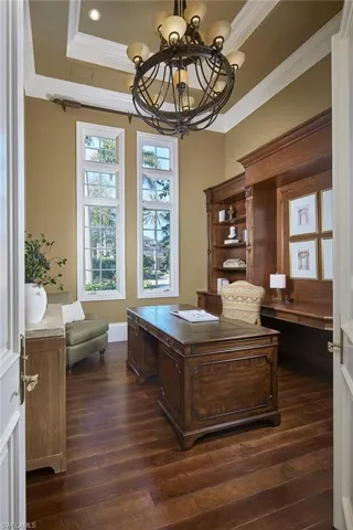 Office area featuring a chandelier, dark wood-style flooring, crown molding, and a tray ceiling