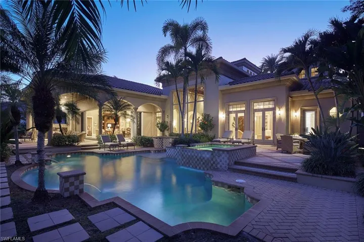 Pool at dusk with a patio, french doors, and a pool with connected hot tub