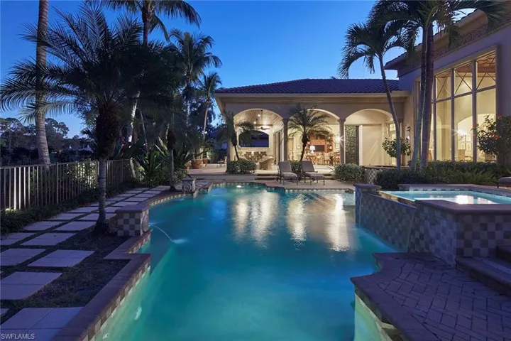 Pool at dusk featuring a patio and a pool with connected hot tub