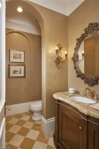 Half bath featuring vanity, ornamental molding, and light flooring