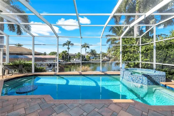 View of swimming pool with a water view, a sunroom, glass enclosure, and a pool with connected hot tub