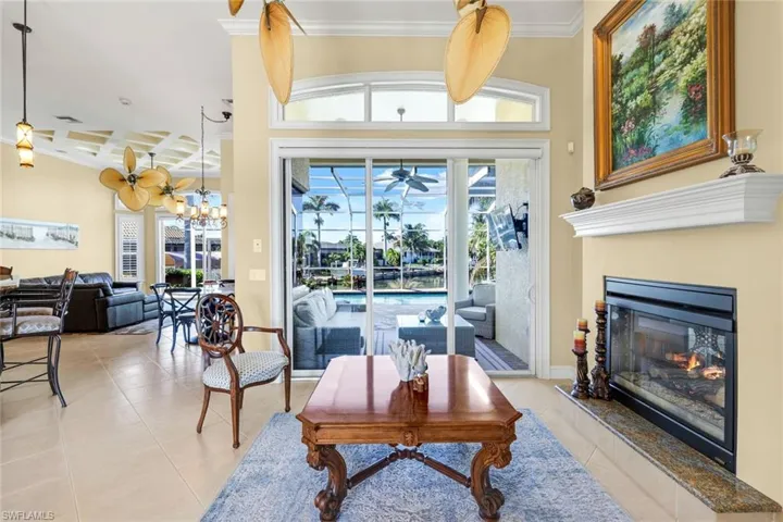 Tiled sitting room featuring crown molding, coffered ceiling, a glass covered fireplace, and beamed ceiling