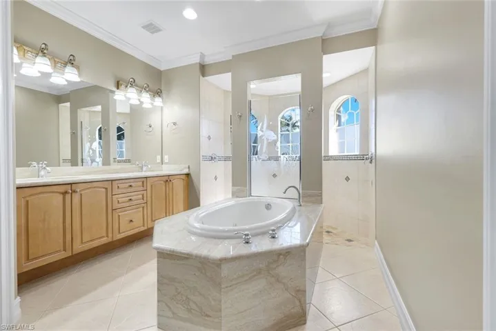 Bathroom with a garden tub, double vanity, a walk in shower, and overflowing natural light